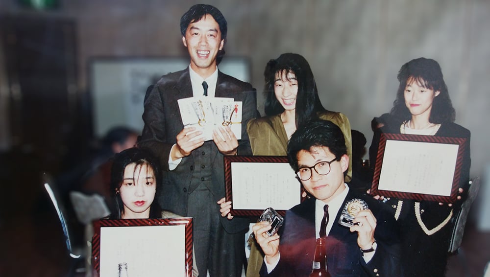 1990年、28歳の頃、社内のFC大会で表彰された時。前列の右側が、松岡氏。